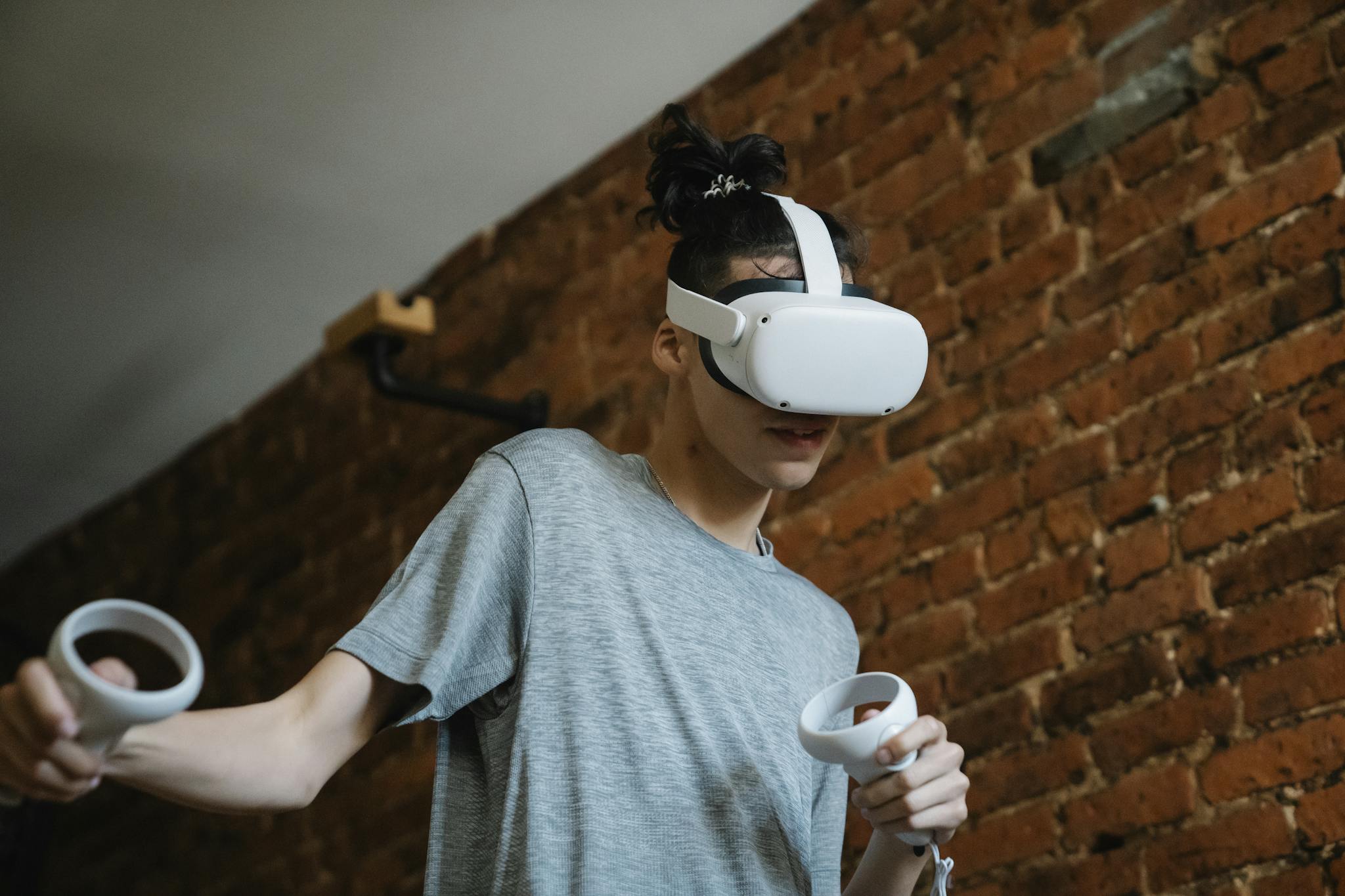 Teen enjoying virtual reality gaming experience with VR headset and controllers indoors.